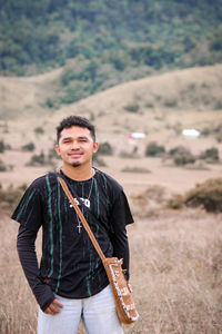 A young man wearing a black t-shirt, jeans and a bag