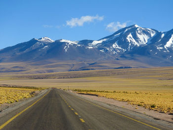Road leading towards mountains against sky