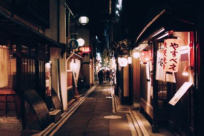 Empty narrow street along buildings at night