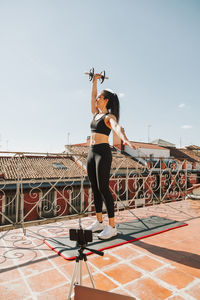 Full length of young woman jumping against sky