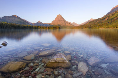 View of mountains reflecting in two medicine lake in glacier park