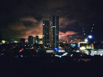 Illuminated buildings in city against sky at night