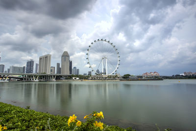 Ferris wheel in city against cloudy sky