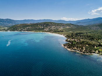 Scenic view of sea and mountains against blue sky