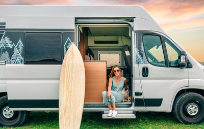 Smiling woman with dog sitting in camper van