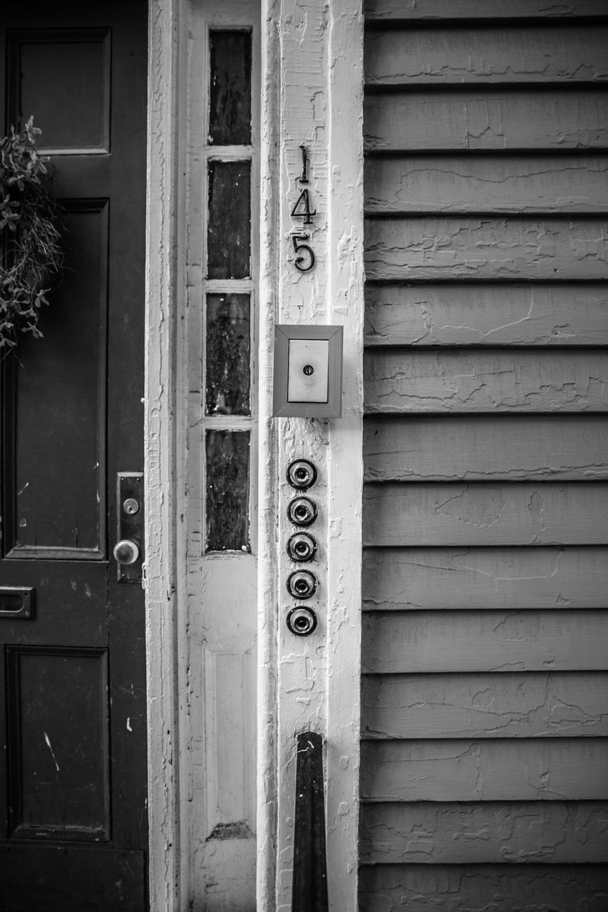 CLOSE-UP OF TEXT ON WOODEN DOOR IN FRONT OF BUILDING