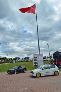 Flag by car against sky in city