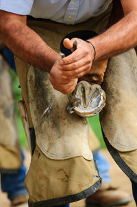 Midsection of man removing horse shoe at stable