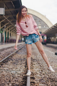 Portrait of smiling woman standing on railroad tracks