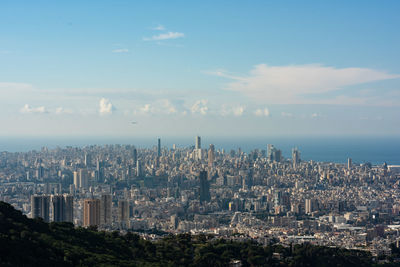 Aerial view of city by sea against sky