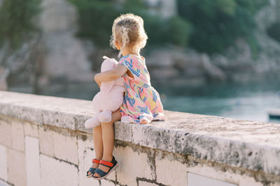 Side view of woman standing on retaining wall