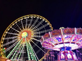 Low angle view of illuminated ferris wheel against sky at night