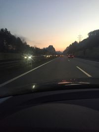 Cars on road against sky during sunset