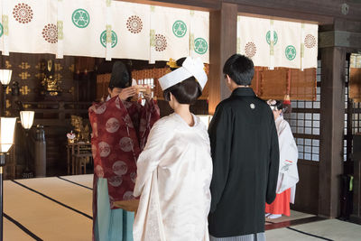 Rear view of people standing against wall