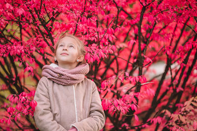 Portrait of woman with pink flowers against trees