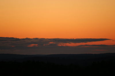 Scenic view of silhouette landscape against orange sky