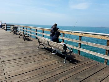 Rear view of people fishing at pier