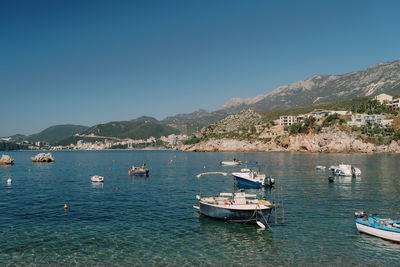 Boats in sea against clear blue sky