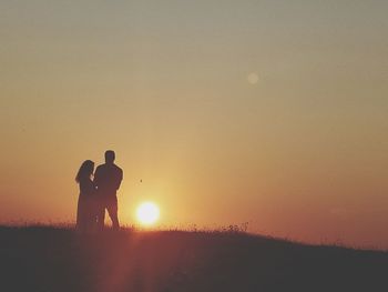 Silhouette man standing against orange sky during sunset