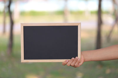 Cropped hand of woman holding blackboard