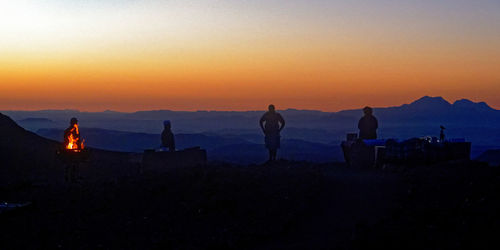 Silhouette people standing on mountain against sky during sunset