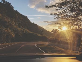 Road seen through car windshield during sunset