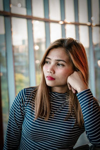 Young woman looking away while leaning on elbow