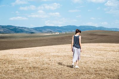 Rear view full length of woman walking on field against mountains