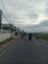 Cars on road against cloudy sky