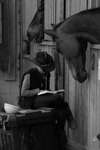 Teenage girl reading book while sitting in stable