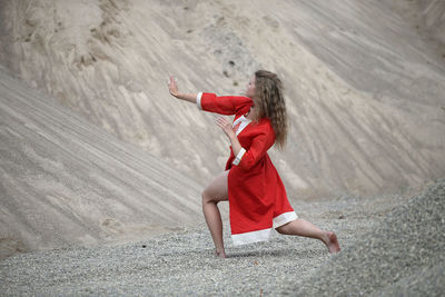 Full length of young woman jumping on sand at desert