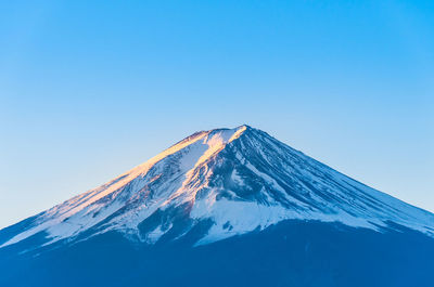 Low angle view of snowcapped mountain against blue sky