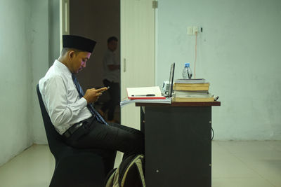 Side view of young man using laptop while sitting at home