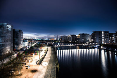 High angle view of illuminated buildings by river against sky