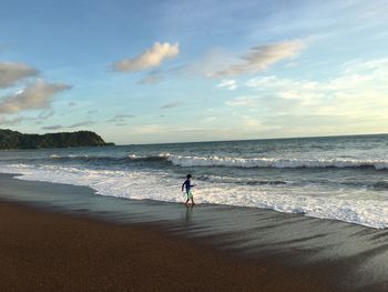 Man standing on beach against sky during sunset