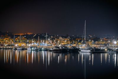 Boats moored at harbor against clear sky at night