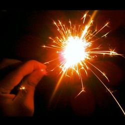 Low angle view of hand holding sparkler at night