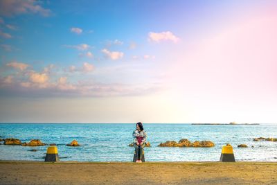 Woman standing on beach against sky
