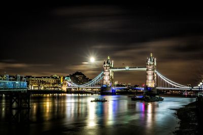 Illuminated tower bridge over thames river against sky at night