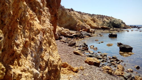 Rock formation on beach against sky