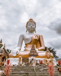 Low angle view of buddha statue against sky