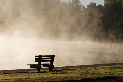 Bench in park by lake during rainy season