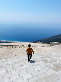 Young boy descenfing scales with mountain sea and sky in background