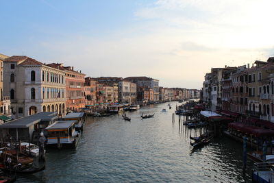 Boats moored at canal against buildings in city