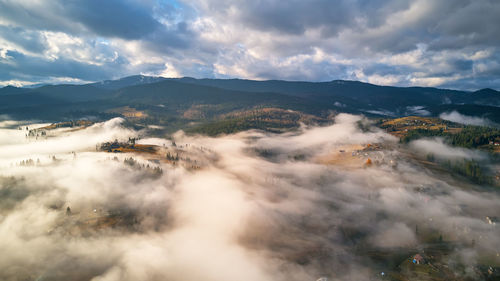 Colorful autumn morning over foggy mountain valley. village covered by clouds.  misty cold  morning