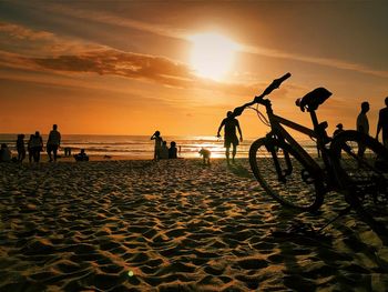 Silhouette people on beach against sky during sunset