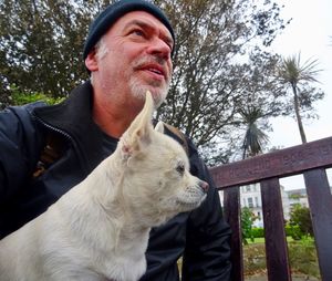 Man looking away with dog against tree