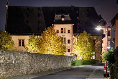 Illuminated street amidst buildings in city at night