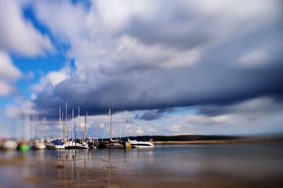 Boats in sea against cloudy sky