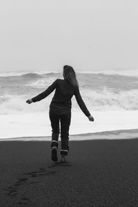 Happy woman walking along black beach monochrome scenic photography